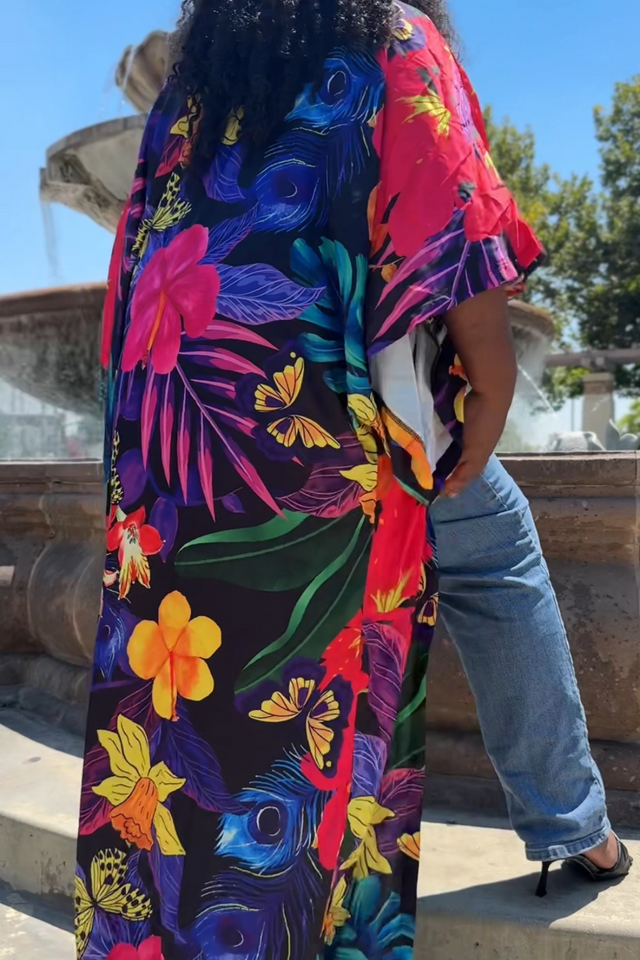 Person wearing a colorful floral kimono with a fountain in the background