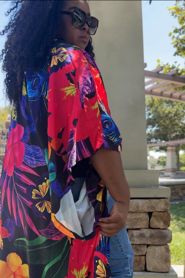 Woman wearing a colorful floral kimono-style garment outdoors.
